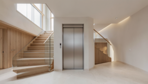 Modern residential elevator doors beside an open staircase in a new-construction home